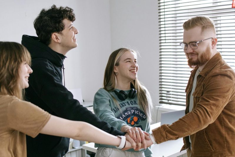 Group of young adults working as a team in a modern office setting.